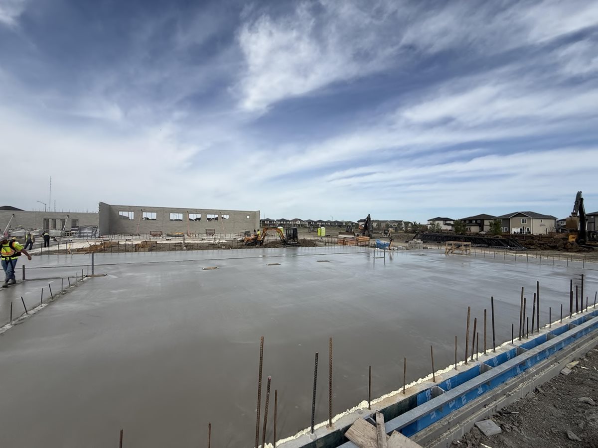 Hollowcore topping concrete pouring at École Iskonakwa School construction site.