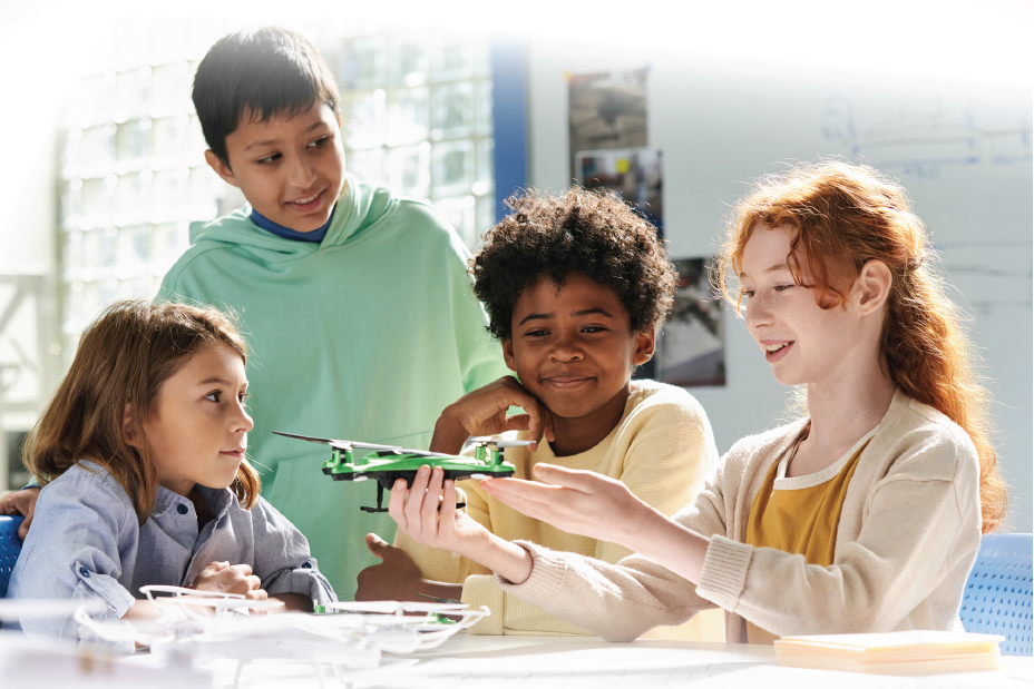Middle school students at a table looking at a model plane.